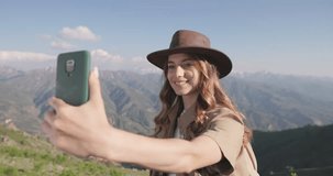 Millennial woman journalist is recording video in mountains for her upcoming travel and hiking article. Woman talks about her impressions and thoughts about her adventure. Active rest in mountains. 
