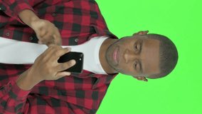 Vertical Video of Young African Man with Loss on Smartphone on Green Background
