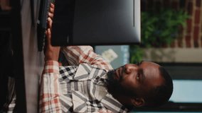 Vertical video: African american male artist working in studio office to create CGI production on software, digital skills. Creative agency designer using professional interface to develop