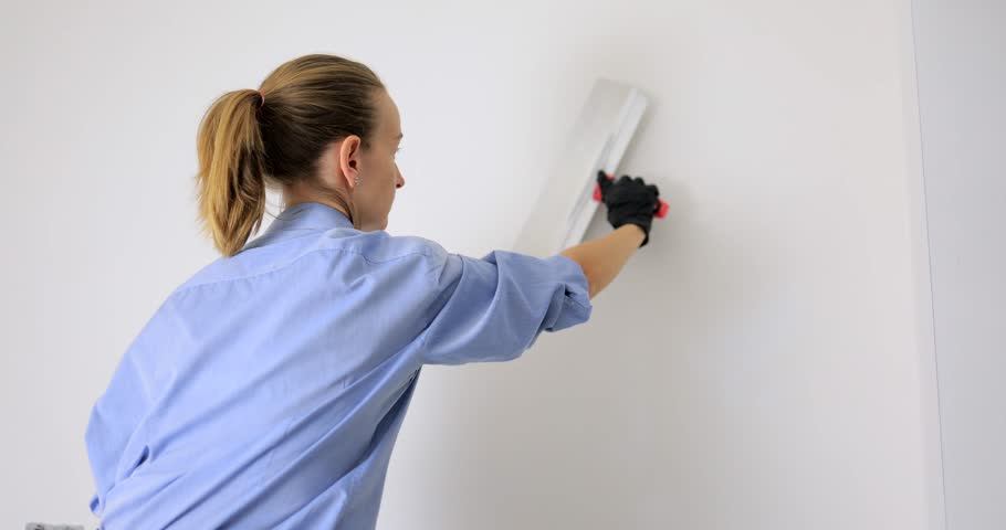 Woman puts putty on the walls with a wide spatula | Shutterstock HD Video #1098306723