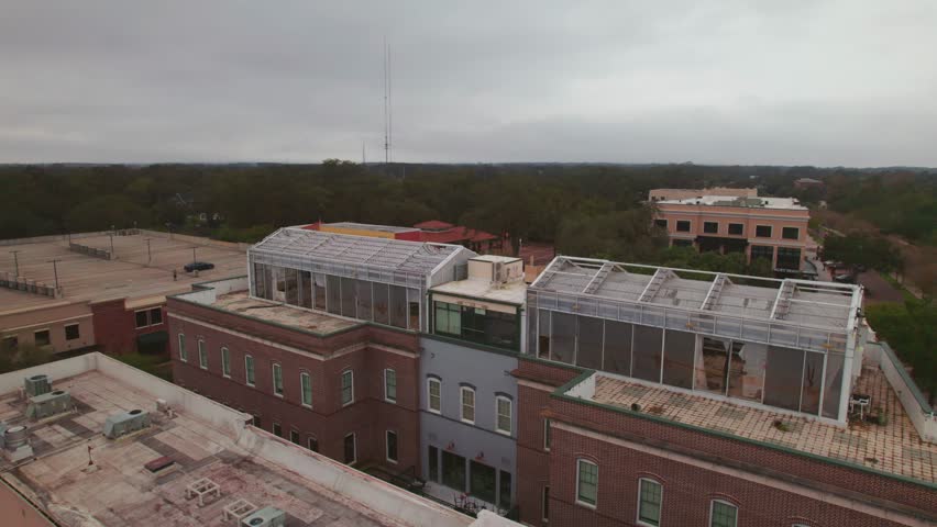 Aerial circle view of the charming and quaint city of Downtown Winter Garden, Florida and a greenhouse on the roof of Garden Theatre.