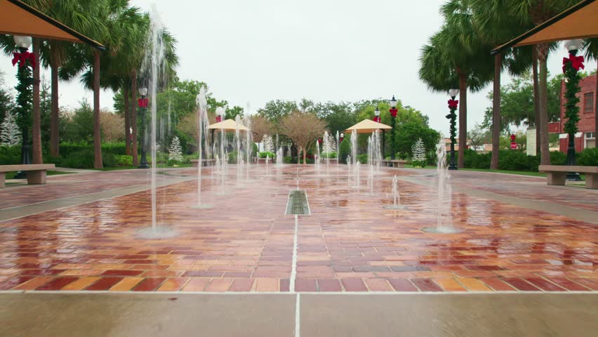 View inside the splash pad of the charming and quaint city of Downtown Winter Garden, Florida as a golf cart passes.