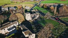 HighaAerial drone video footage of a small village of Hartshead with church and church yard, with gravestones and warm sunlight. Hartshead Moor, West Yorkshire, UK