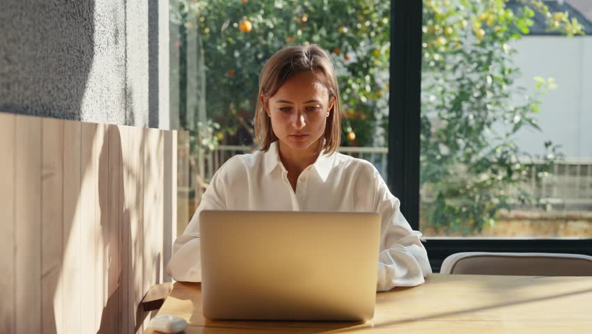 Young Beautiful caucasian woman Works on a Laptop Computer in Cool Creative Agency in a Loft Office. She has a Take-away Coffee and a Notebook on Her Table.High quality 4k footage
