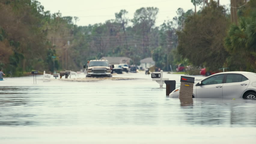 Flooded town street with moving cars submerged under water in Florida residential area after hurricane Ian landfall. Consequences of natural disaster | Shutterstock HD Video #1098320263
