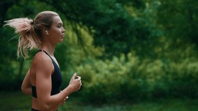 Side view of the female runner running wearing earphones in the park. Sportswoman morning jogging training. People, sport and technology concept - Powered by Shutterstock - Get 15% off with code: PIKWIZARD15