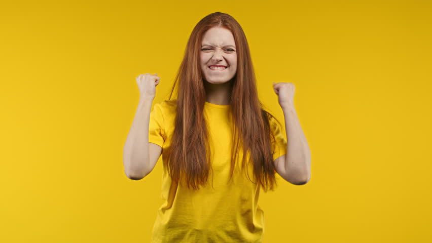 Pretty woman shows triumph yes yeah gesture of victory, achieved result, goals. Girl glad, happy, surprised excited happy lady on yellow background. Victory concept. | Shutterstock HD Video #1098323291