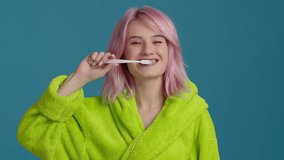 Deep teeth cleaning. Mirror pov portrait of young hipster girl with pastel pink hair brushing teeth with toothbrush. Young woman in neon robe caring about dental hygiene at home in morning slow motion - Powered by Shutterstock - Get 15% off with code: PIKWIZARD15