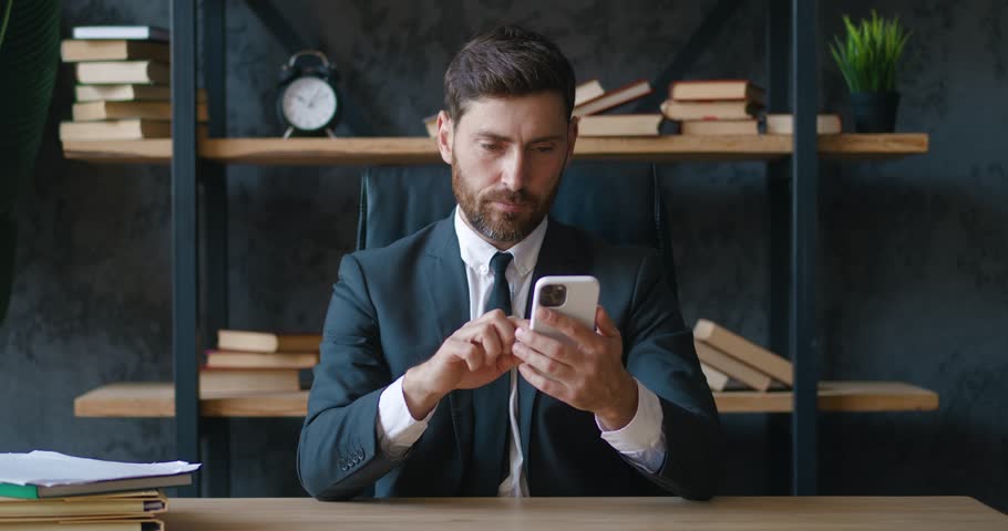 Frustrated man entrepreneur reading bad news on smartphone while sitting in office. Shocked by bad message man entrepreneur experiencing emotional stress at workplace. Losing concept | Shutterstock HD Video #1098323811