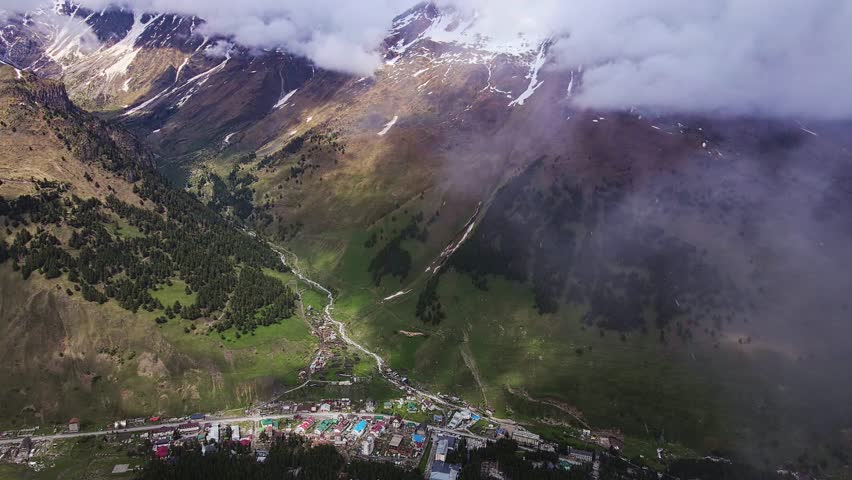 A view from above of an eagle flying over a beautiful valley. The Caucasus mountains, Terskol. Animals in the wild. Breathtaking summer landscape. Drone flying through the falling snow