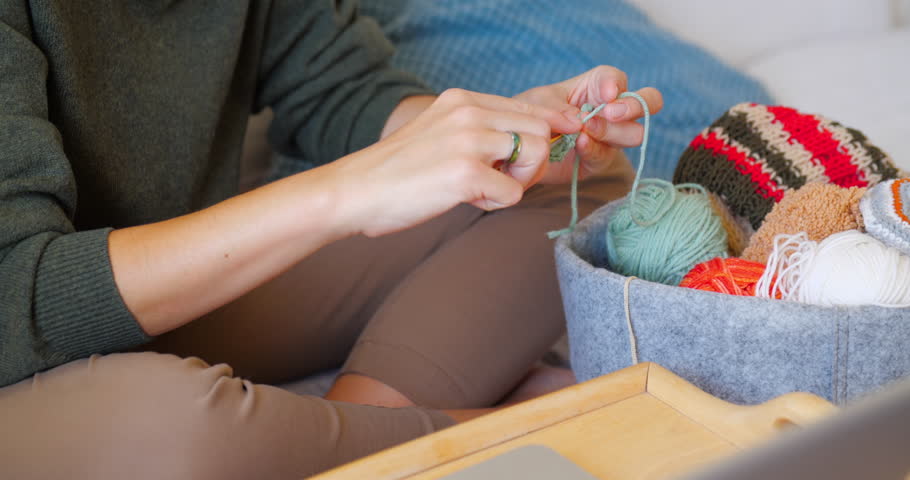 Close-up video of woman crocheting something small. Anti-stress hobby. Tranquil leisure at home. Handicraft.