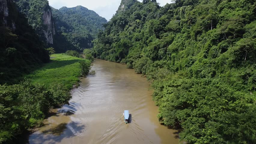 A tourist boat sails along the river between mountains and green forests in Asia, Around the jungle and nature Royalty-Free Stock Footage #1098329771