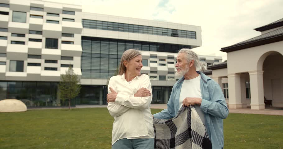 Mature husband and wife hugging standing outside building