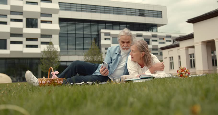 Senior age couple enjoying picnic together on meadow