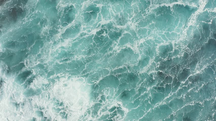 Beautiful aerial top down view of turquoise blue ocean waves crashing and rolling on top of coastline reef rocks. White foam and water ripple. Camera rotate right. 4k footage. Royalty-Free Stock Footage #1098331963