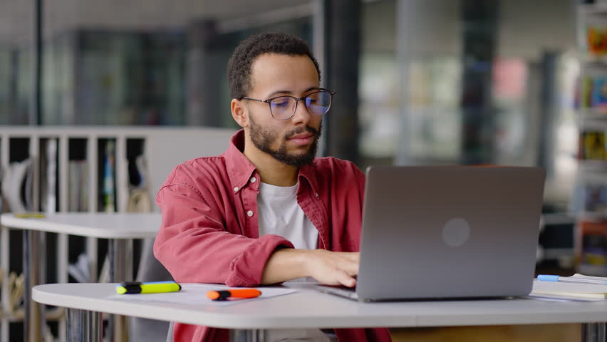 Overworked young multiethnic postgraduate student lecturer, taking off glasses, massaging temples while finishing online lesson. Young student feeling tired after long work at laptop in library campus Royalty-Free Stock Footage #1098332237
