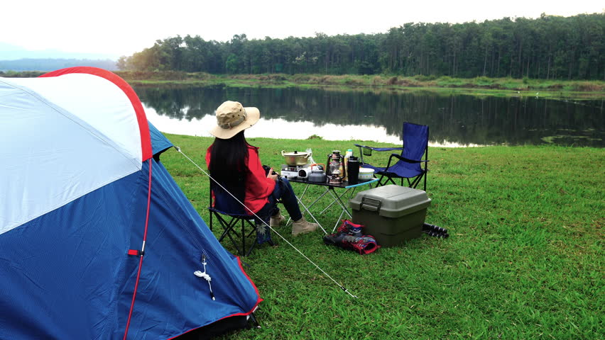 Woman taking photos with camera while camping in morning.