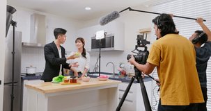 Asian videographer filming video about healthy eating in studio with crew member
