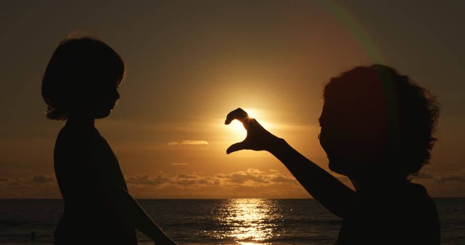 mother and little son silhouette at sunset, Hands of woman and her child made a heart shape at sunset. Happiness and freedom, dream of motherhood concept, happy mother and child, emotional scene