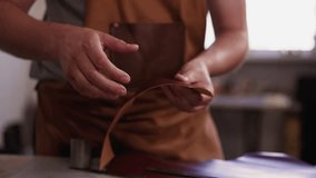 Master bends and turns leather detail of craft accessory in workshop close view. Leather goods manufacturer makes original item in studio. Manual work industry - Powered by Shutterstock - Get 15% off with code: PIKWIZARD15