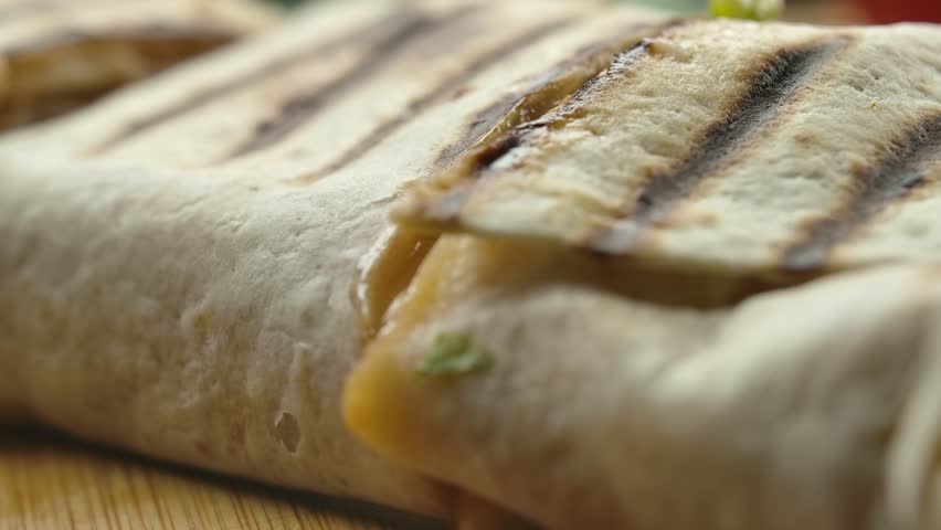 Super close-up of mexican burrito with melted cheese and Juicy pieces of meat and vegetables fall out of the burrito. High quality 4k footage Royalty-Free Stock Footage #1098354995