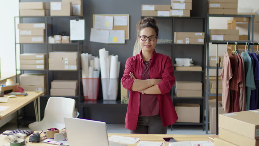 Medium long shot of female manager posing for camera with arms crossed and smile during workday in delivery service office - Powered by Shutterstock - Get 15% off with code: PIKWIZARD15