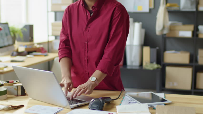 Delivery service worker bringing parcels to female colleague, she scanning barcodes on boxes and using laptop while working together in office | Shutterstock HD Video #1098362949