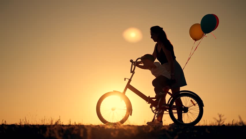 Happy family. Mom teaches son to ride bike. Concept of children holiday and dreams. Family playing in park at sunset. Silhouette of mom and son on a bike in the park. Green energy. Mom teaches son. | Shutterstock HD Video #1098372153