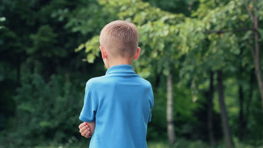 Child turns from his back and looks at the camera smiling. Portrait of a boy in a blue shirt.