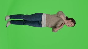 Vertical video: Side view of full body person doing t shape symbol on green screen background, showing break or timeout gesture with arms. Negative girl standing over greenscreen with refusal