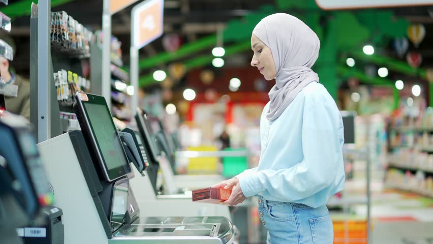 Female buyer using a self-service cashier checkout in a supermarket. Customer scanning produce items using at grocery store self serve cash register. cashier terminal woman pay for products online  | Shutterstock HD Video #1098378717