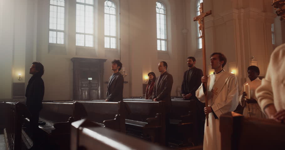 Liturgy in Grand Church: Majestic Procession Of Ministers And Priests Walking with Processional Cross. Congregation Stands In Reverence, Christians Rejoice In Ceremony of Mass. Slow Motion Pan Shot