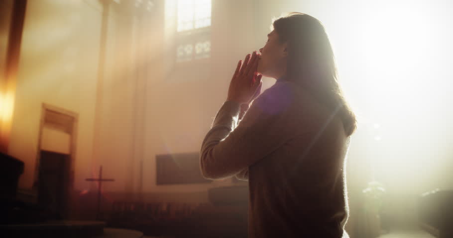 Christian Young Woman Starts Praying Under the Blessed Lights in a Church, Her Thoughts Turning To The Divine Jesus Christ, the Bible and its Teaching. Finds Strength in Sacred Religious Space Royalty-Free Stock Footage #1098381111