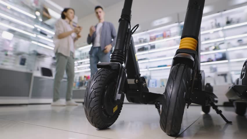 A man and a woman in a shopping mall in an electronic goods store. A couple chooses an urban electric scooter.