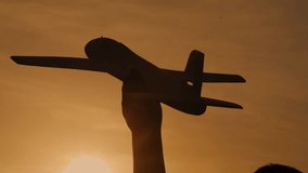 Close-up Silhouette of a child's hand launching a toy airplane into the air at sunset. The boy dreams of becoming an airplane pilot. A childhood dream. Happy boy with a toy - Powered by Shutterstock - Get 15% off with code: PIKWIZARD15