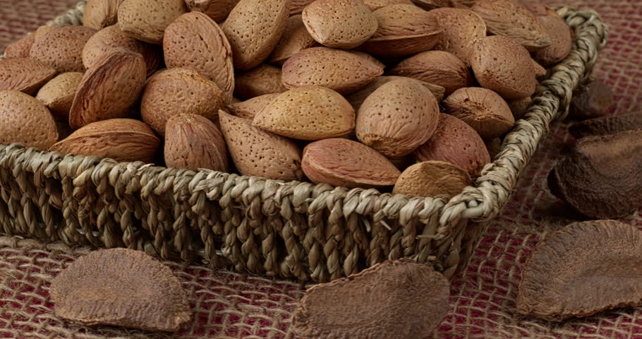Unshelled almonds in braided basket and unshelled Brazil nuts. Table spin. 