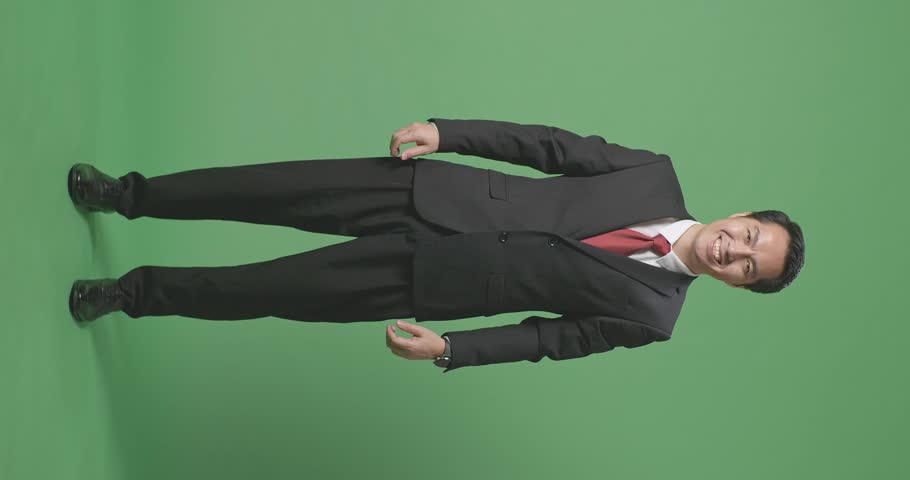 Full Body Of Asian Business Man In Classic Shirt And Red Necktie Buttoning Jacket. Dressing For Celebration Event, Business Meeting Or Wedding On Green Screen Background
