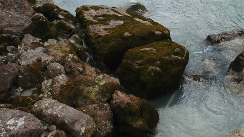 Tilt up from river rocks revealing Glacier River in Alberta, Canada.
