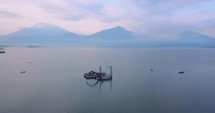 Aerial view of dredger boat with fishing boats all around. Beautiful lake with mountain on the background. Rawa Pening Lake, Indonesia