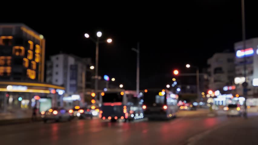 Cars are parked at night at a city traffic light out of focus, two buses at a traffic light without a focus frame. Red traffic light. High quality 4k footage