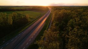 AERIAL: Convoy of cargo trucks on a countryside highway in beautiful golden light. Low traffic on a motorway that crosses beautiful landscape in gorgeous light. Truck transport for delivering goods.