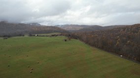 Aerial Drone Video of a Red Barn in a Farm with a Cloud Covered Mountain on a Moody Fall Day