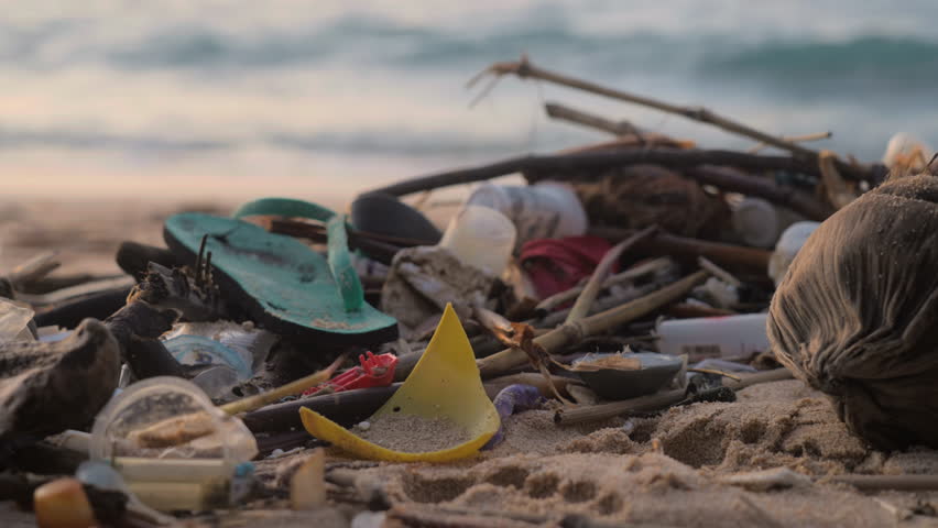 Pile of plastic and wooden garbage on a beautiful white sand beach at ocean shore. Heap of rubbish on seaside. Nature polluted with trash and indifferent people. Human life consequence.