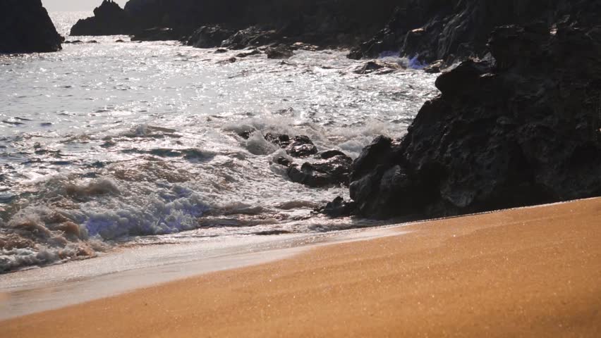 Slow motion shot of sea waves striking the rocks at the shore of Kakolem Beach in Goa, India. Sea waves at the beach. Natural background. Sea waves striking on the rocks at the beach and breaking off.