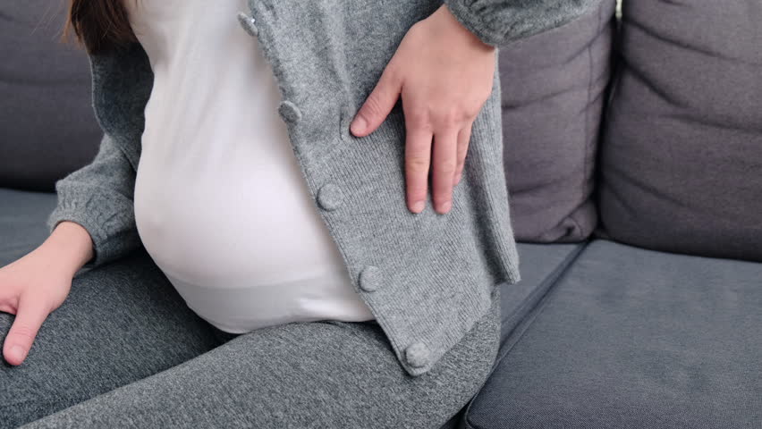 Close up side view of young pregnant woman massaging back muscles sitting on sofa, suffering from severe painful feelings, female 20s  with third trimester big belly having joints strain in lower back Royalty-Free Stock Footage #1098410757