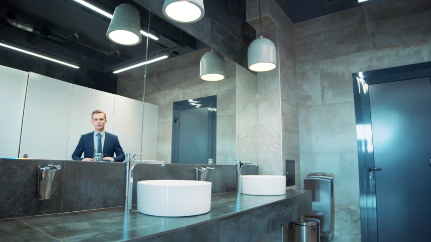 Business man in office bathroom. Stressed manager using restrooms, washroom and lavatories while looking at receding hairline. Male beauty in public toilet with businessman checking hair for loss Royalty-Free Stock Footage #1098416505