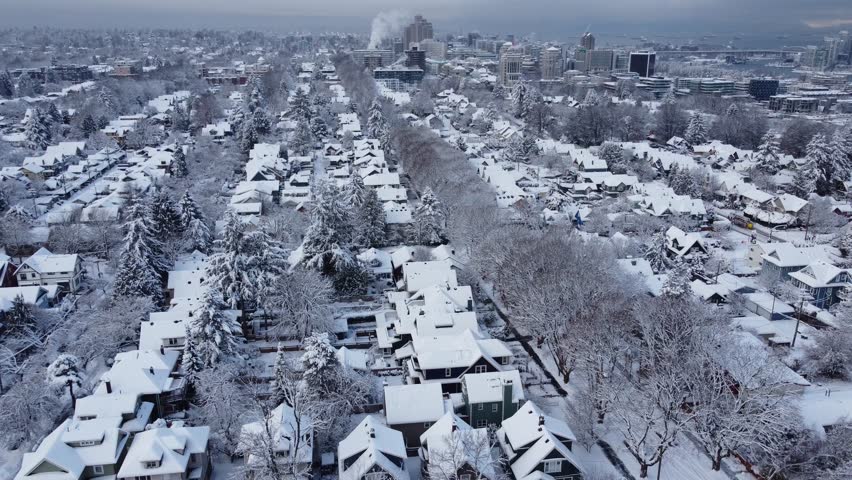 Fly over small houses, trees and roads with a snow in Vancouver