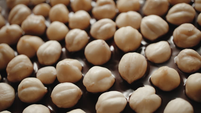 Close-up whole hazelnuts pouring with hot melted chocolate, flowing molten milk chocolate or brown caramel sauce and nuts. Cooking chocolate bar, dessert, candies. Confectionery manufacture Royalty-Free Stock Footage #1098418007