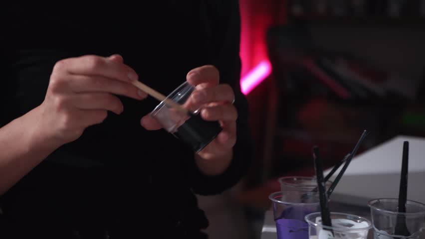 A girl artist kneads paint in a plastic cup. The process of preparing acrylic drawing