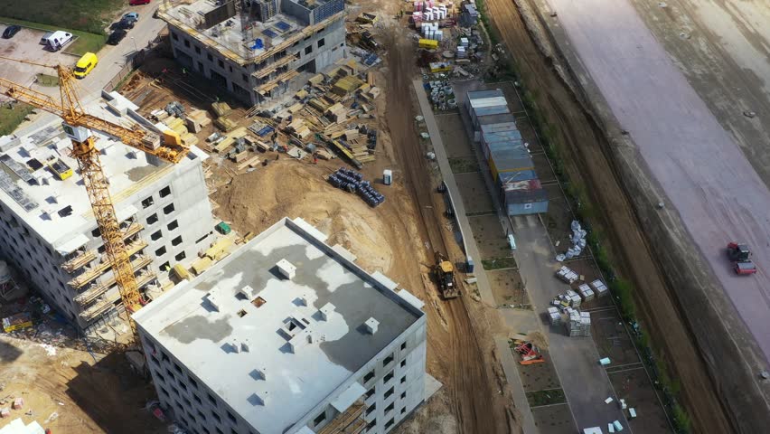 Aerial Flight Over a New Constructions Development Site with High Tower Cranes Building Real Estate. Heavy Machinery and Construction Workers are Employed. Top Down View at Contractors in Safety Hats. | Shutterstock HD Video #1098421109
